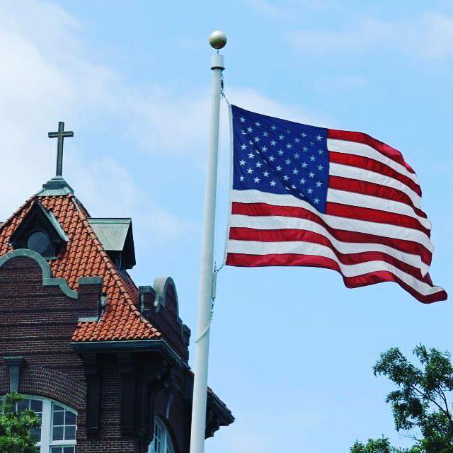 The American flag flies over Alumni Hall.