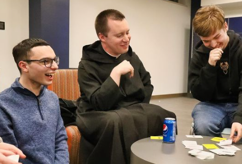 Students Tom Canuel and Brendan Fedrizzi play cards with Br. Ignatius Membrino