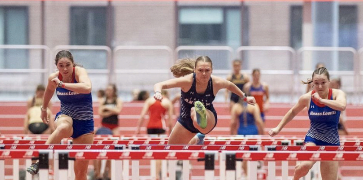 Freshman runner Lydia Belanger hurdling during a meet at the New Balance Track in Boston MA.